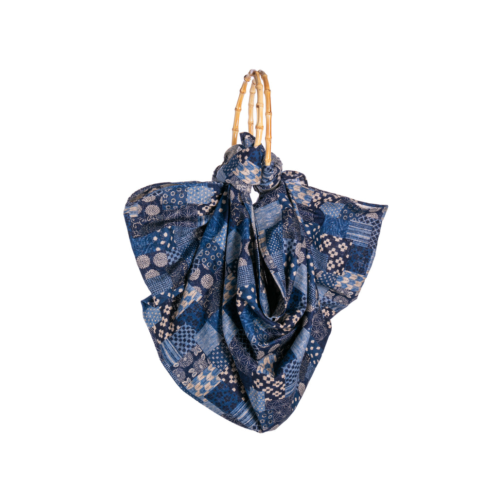 Furoshiki is a traditional Japanese fabric wrap. In a dark blue, this cotton fabric is wrapped around the bamboo handles. With a Japanese-inspired pattern, this bag is lightweight and is perfect for your daily essentials. Materials: Cotton, Bamboo handle Dimensions: Approx. 19" Length from handles (when held upright)