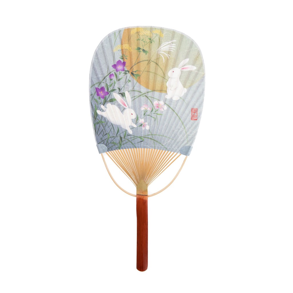 The Uchiwa fan is an indispensable item during Japanese summer. These beautifully constructed fans are traditionally used for both fanning and also for repelling mosquitos and flies. Bamboo handle and frame. Decorated with a print featuring bunnies in a zen garden. Size: 14.5" x 7".