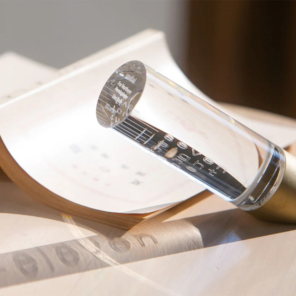 This simple yet clever 'undial' serves as a free-standing sundial. As sunlight passes through a cylindrical lens, the ever-changing time is projected onto the table. Materials: Acrylic, Brass. Designed in Japan by Atsuhiro Hayashi. Dimensions: 5.7" x 2.8" x 4.1".