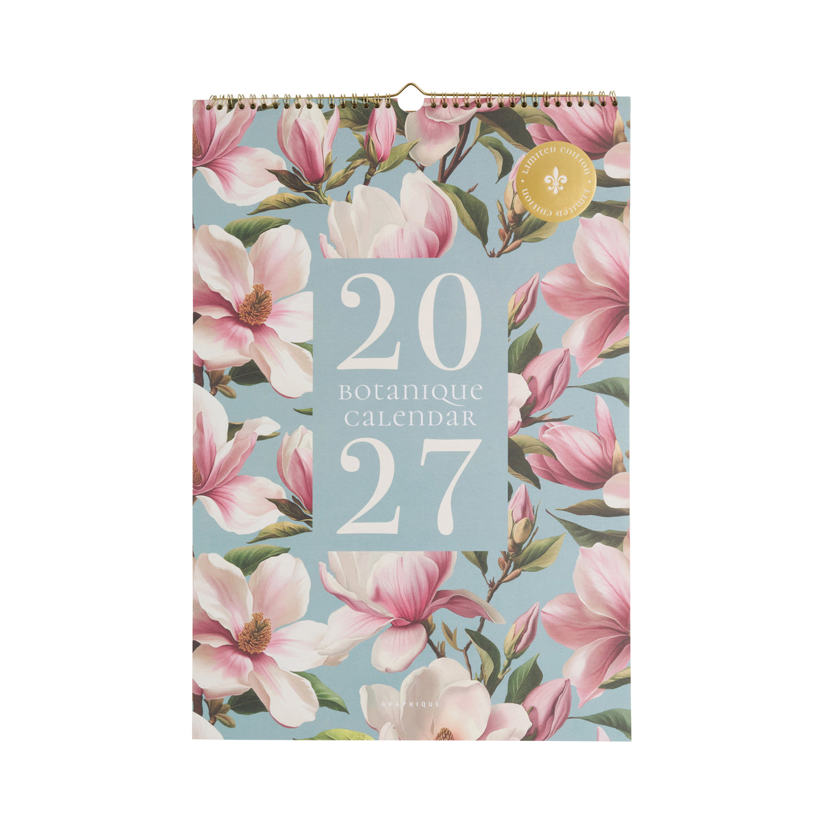 A 2027 botanical wall calendar with a light blue background and a pink magnolia floral pattern, featuring a gold spiral binding at the top.