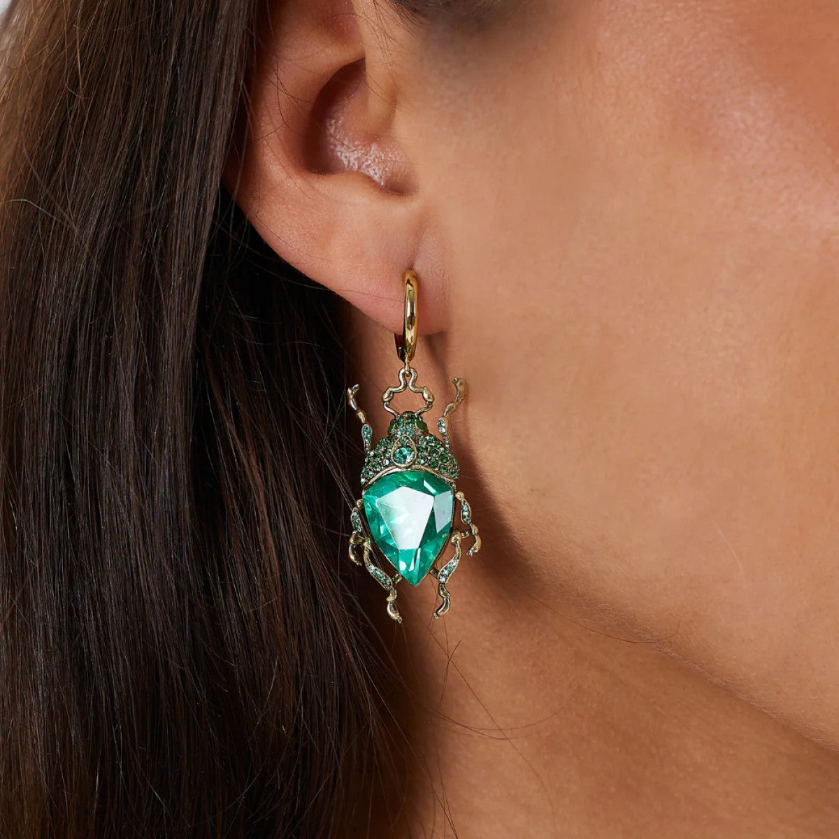 Pair of green gemstone bug earrings with gold accents on a white background