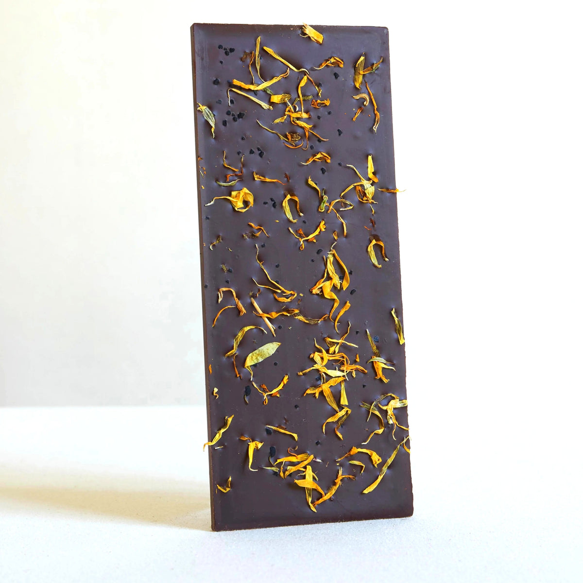 Dark chocolate bar with flower petals on a white background
