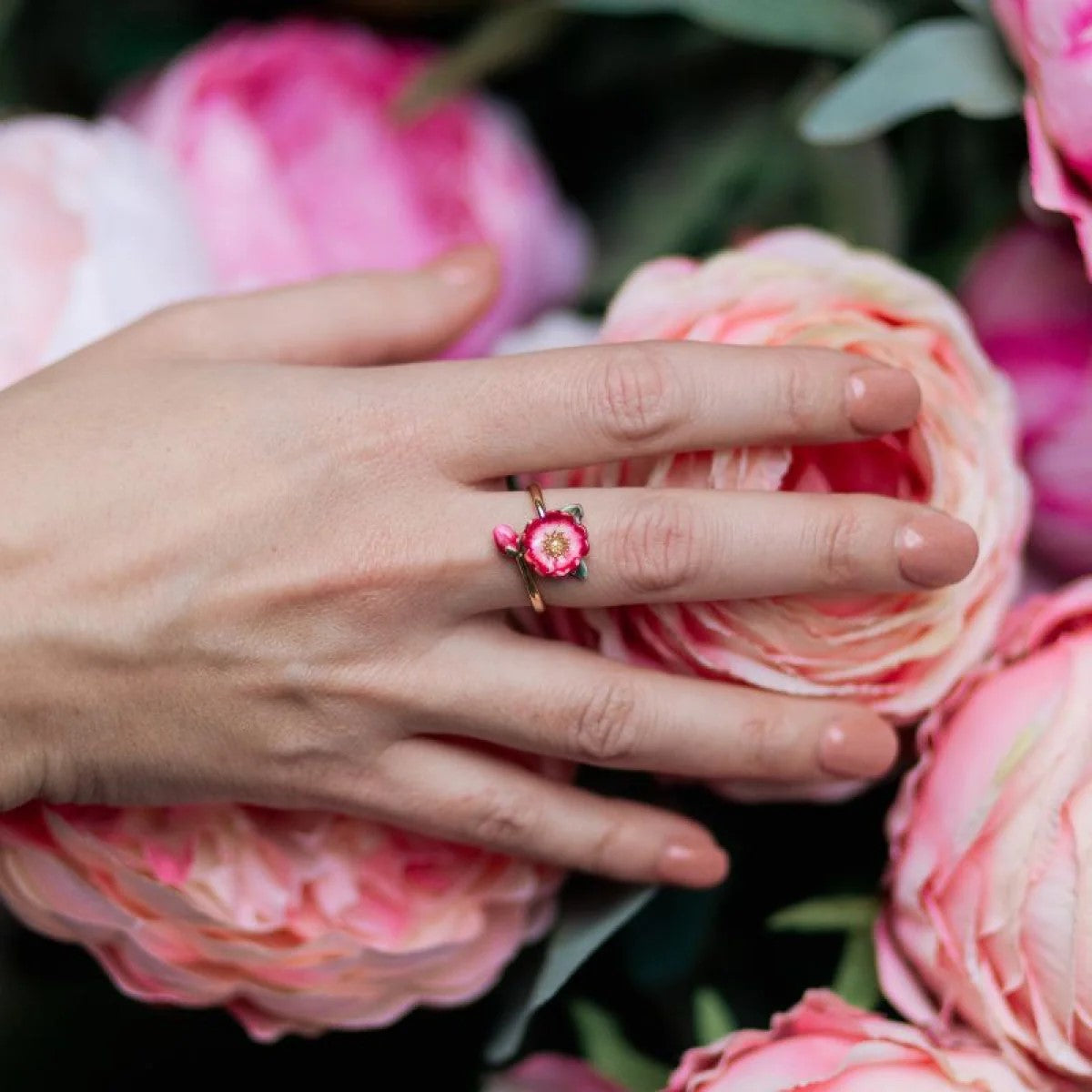 Gold ring with a red flower-shaped gemstone on a white background