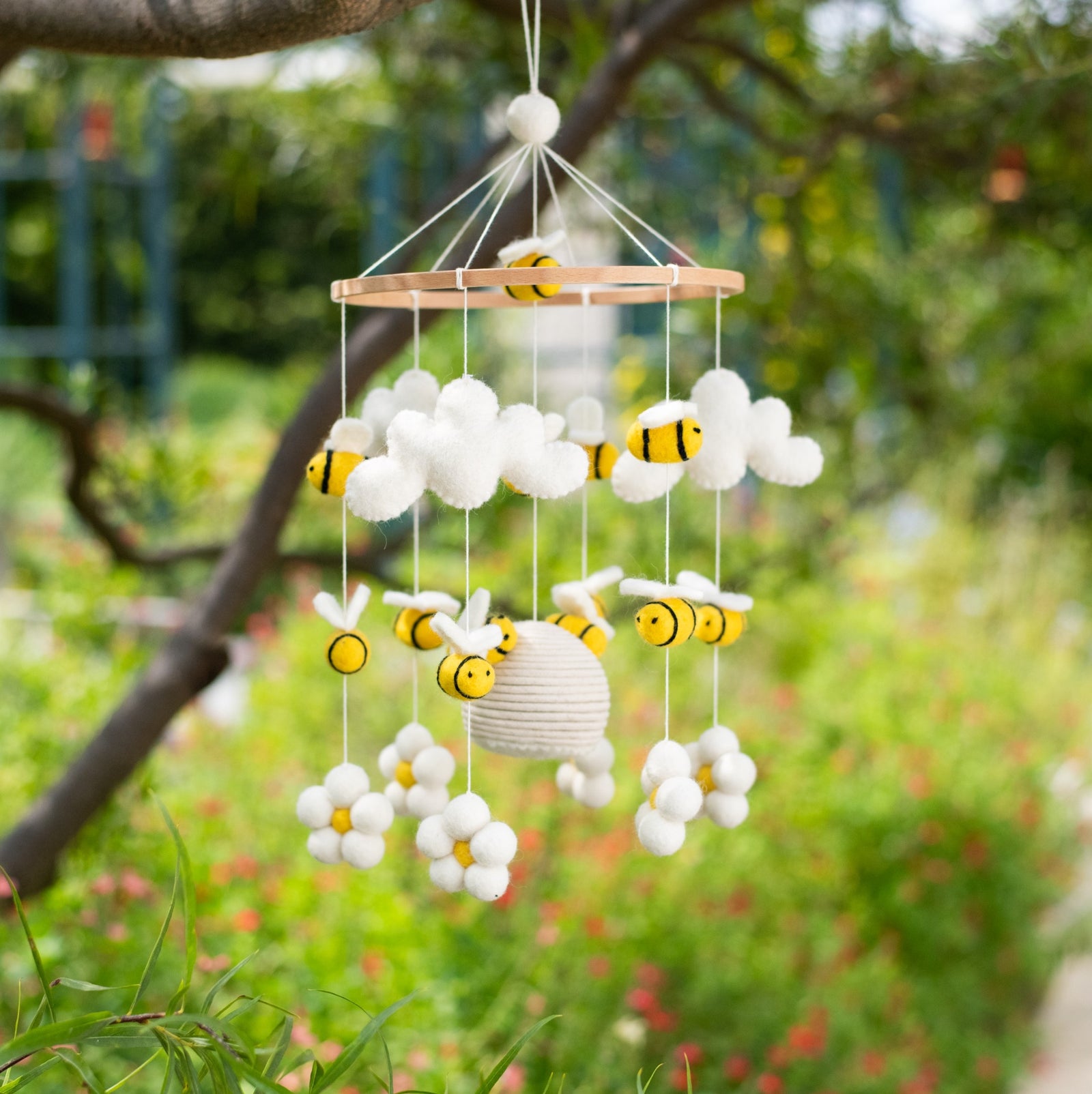 Baby mobile with flowers, bees, and a beehive on a white background