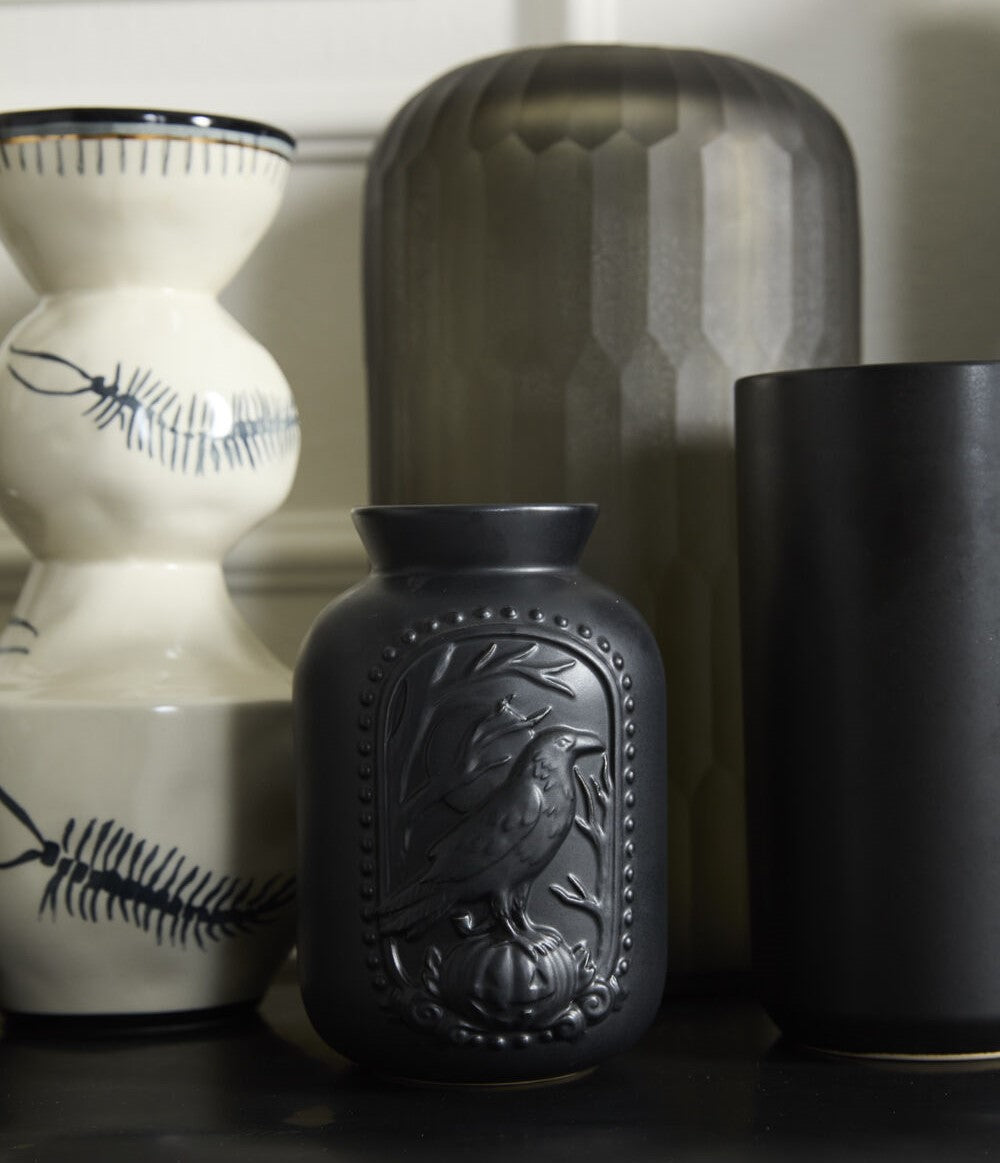 Black vase with a bird design on a white background