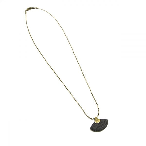 This contemporary jewelry piece is handmade using Binchotan, or Japanese wood charcoal. This exceptional natural material has been used in Japanese arts and crafts for centuries and is used here to create unique and stunning jewelry pieces. This pendant necklace features polished charcoal in the shape of a ginkgo leaf, trimmed with antique brass.