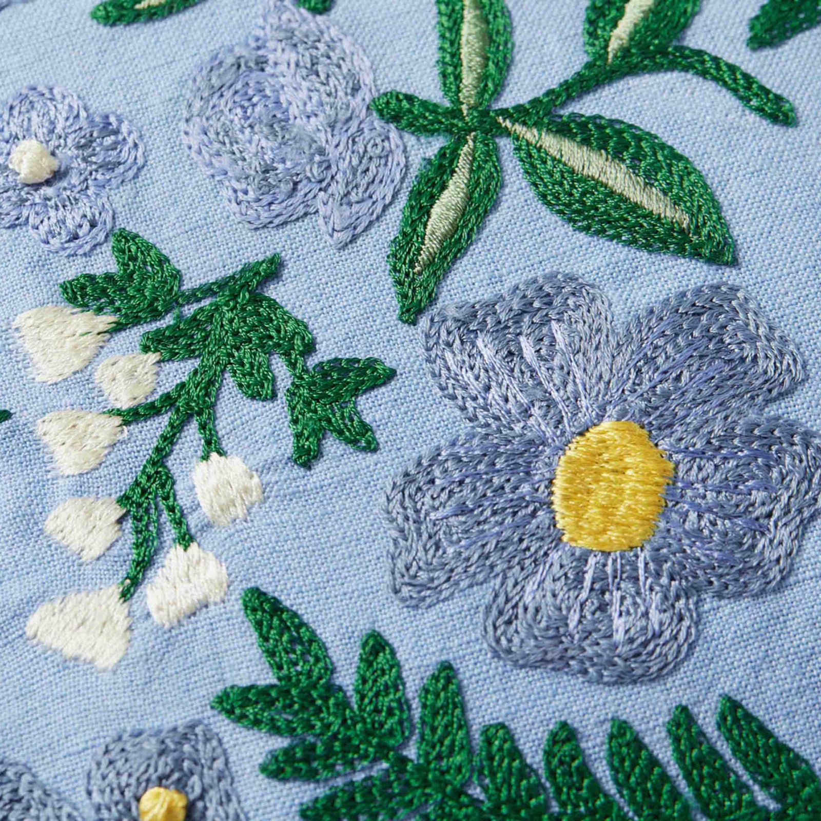 Pretty periwinkle blue lumbar pillow with woodland wildflower embroidery, French knots, cotton, linen, polyester, 21" x 13", down-filled insert, zipper closure.