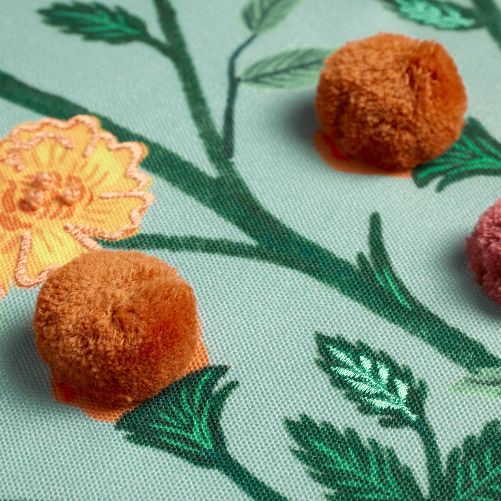 Golden marigolds with detailed embroidery and pom poms adorn this throw pillow. Adds color and comfort to any room. Polyester, 22"x22", down-filled insert.