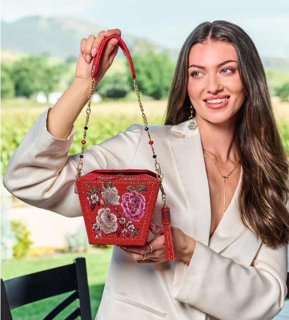 Woman holding a red handbag with floral embroidery outdoors