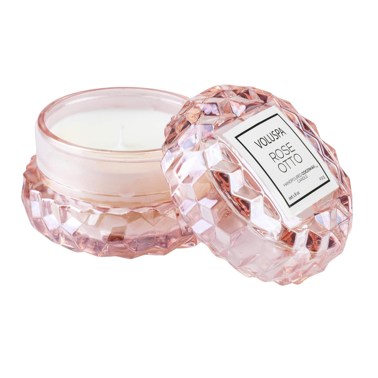 A rose scented candle in a pink carved glass jar on a white background