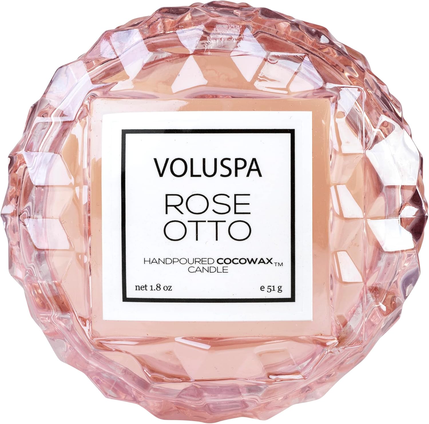 A rose scented candle in a pink carved glass jar on a white background