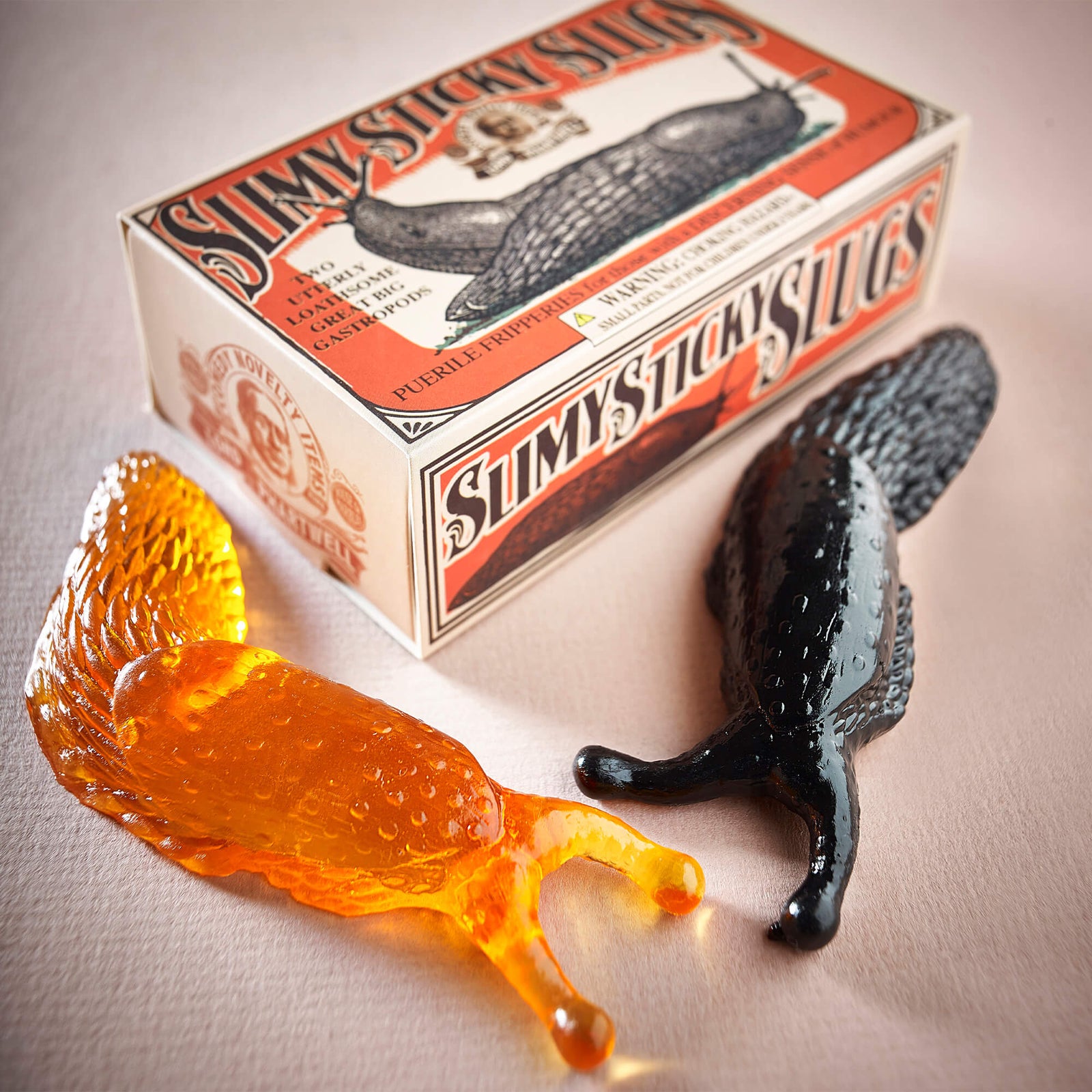Toy slugs with packaging labeled 'Slimy Sticky Slugs' on a white background