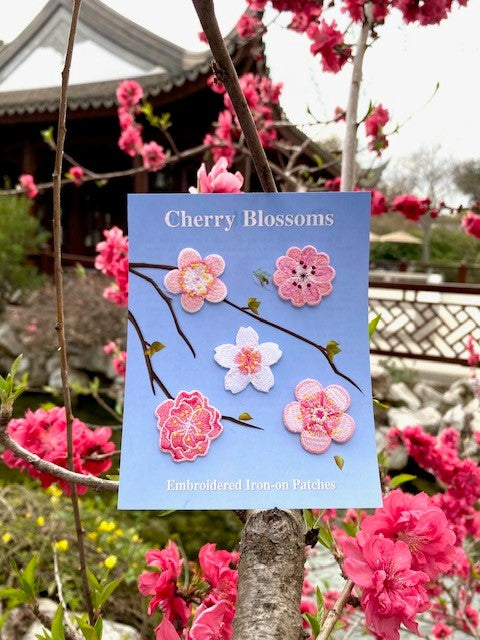 Packaging of cherry blossom embroidered iron-on patches with a blue background