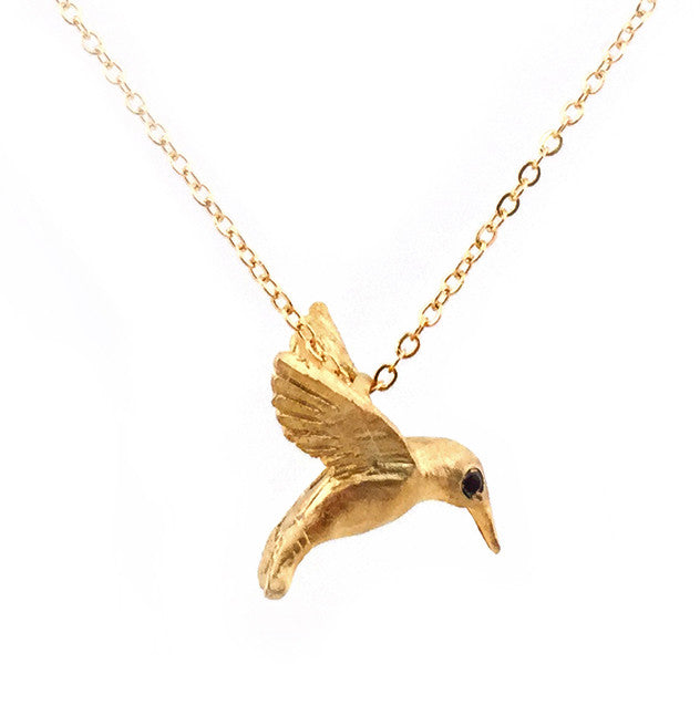 Wear this sweet hummingbird necklace each time you want to reminded of warm, carefree days. This most delicate of birds is captured here mid-flight. Black diamond eyes add a touch of luxurious sparkle. 18K gold plate over sterling silver Black diamond accents 16", 14K gold filled chain Pendant is approximately 1/2".