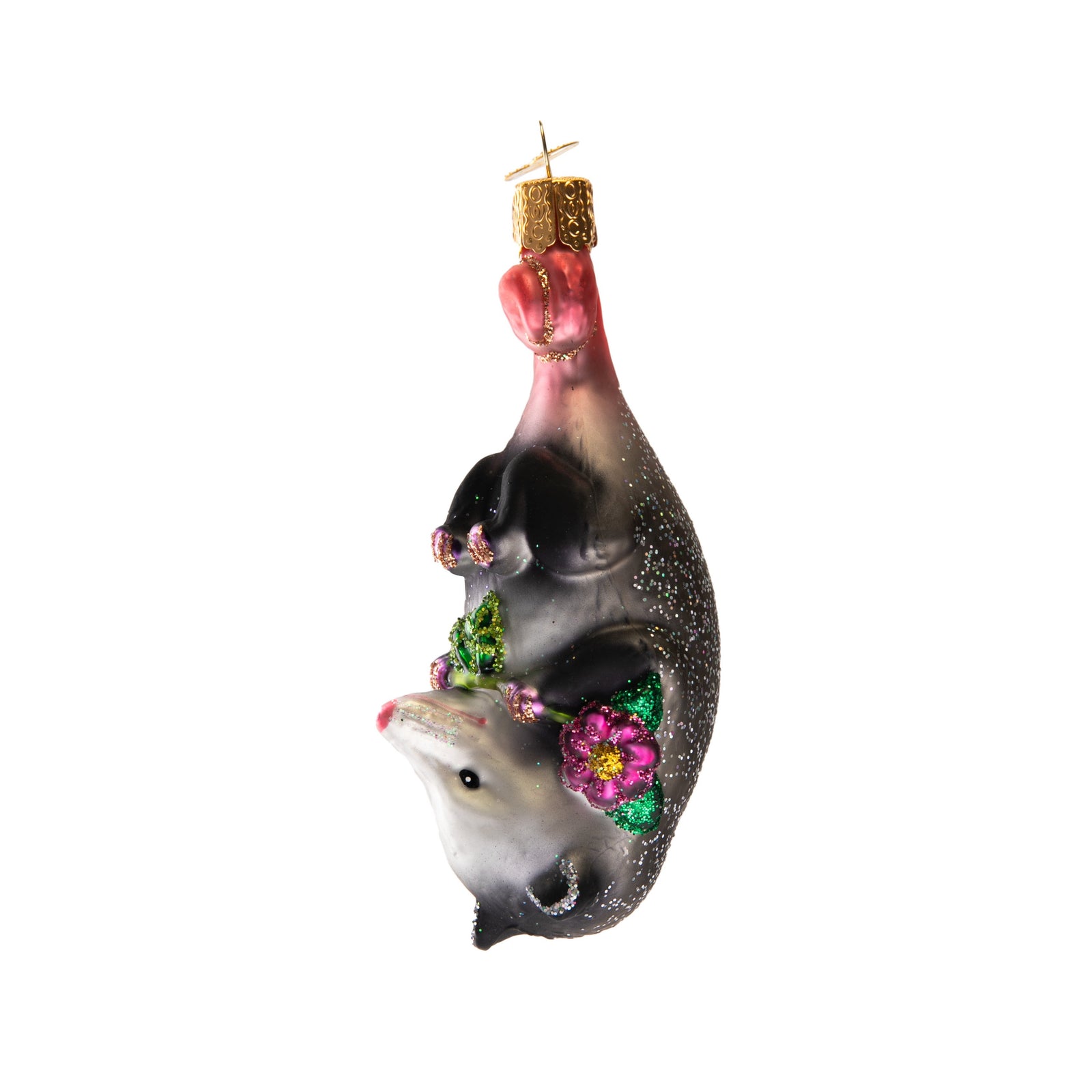 This adorable creature is hardly playing possum as she snuggles a beautiful blossom. Opossums are unique for using their tail as a fifth limb as they climb, hang and balance, hence why this cute Opossum ornament hangs upside down! Glass Ornament Hand painted and glittered Approx 4.25" x1.5"