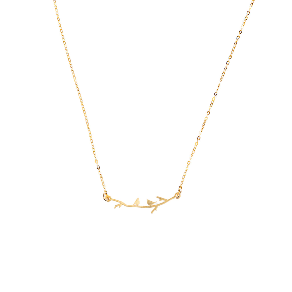 Two tiny, silhouetted birds sit atop a delicate branch on this sweet, dainty necklace. This necklace is the perfect gift for anyone who loves nature or all things aviary. Wear it as a unique statement piece to elevate your look. Gold-filled chain Chain length: 16" (including branch detail).
