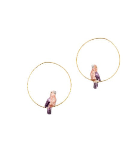 Add a tropical touch to your outfit with these adorable porcelain parrot hoop earrings. The porcelain parrots are painted by hand, making each pair of earrings unique. Porcelain and 24k gold plated brass earrings Designed in Toulouse, France Hoop diameter: 1.5"