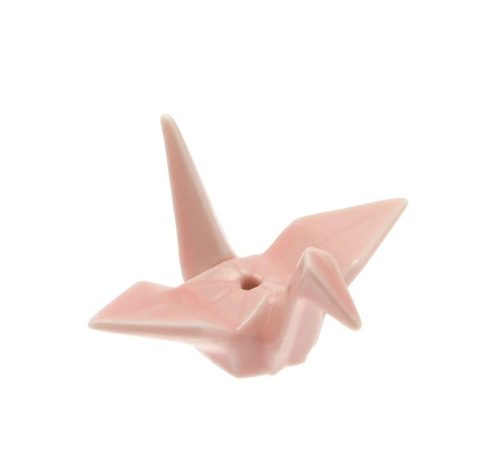 The crane's tall stance and powerful flight pattern make it the perfect symbol of power and strength, representing good fortune and longevity. Bring good fortune into your home with this ceramic origami crane, which is perfectly poised to hold your incense sticks. Ceramic with a pink glaze. Size: 2.5" x 1.25" x 2".