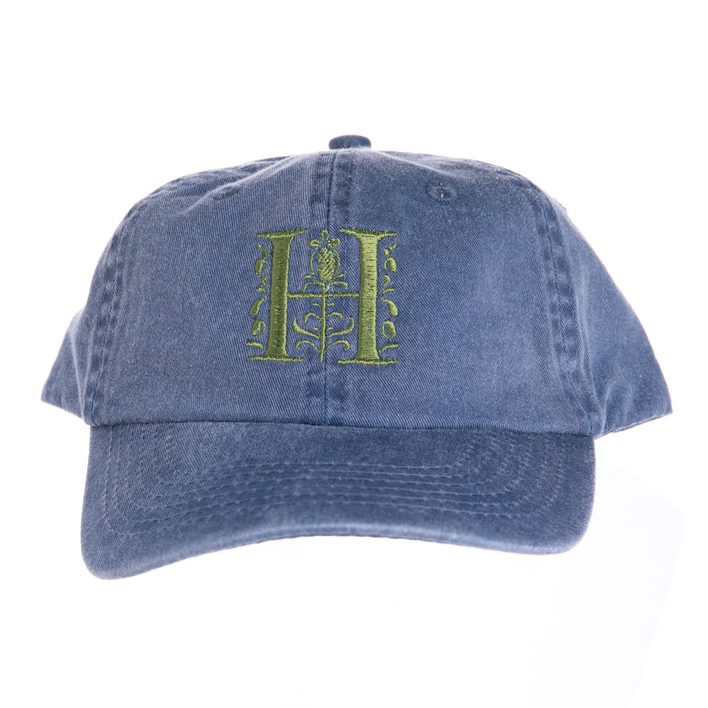 Signature "H" logo embroidered in green on a blue cap. Hat band circumference: 22" + 3" adjustable velcro strap at the back 100% cotton Huntington Exclusive