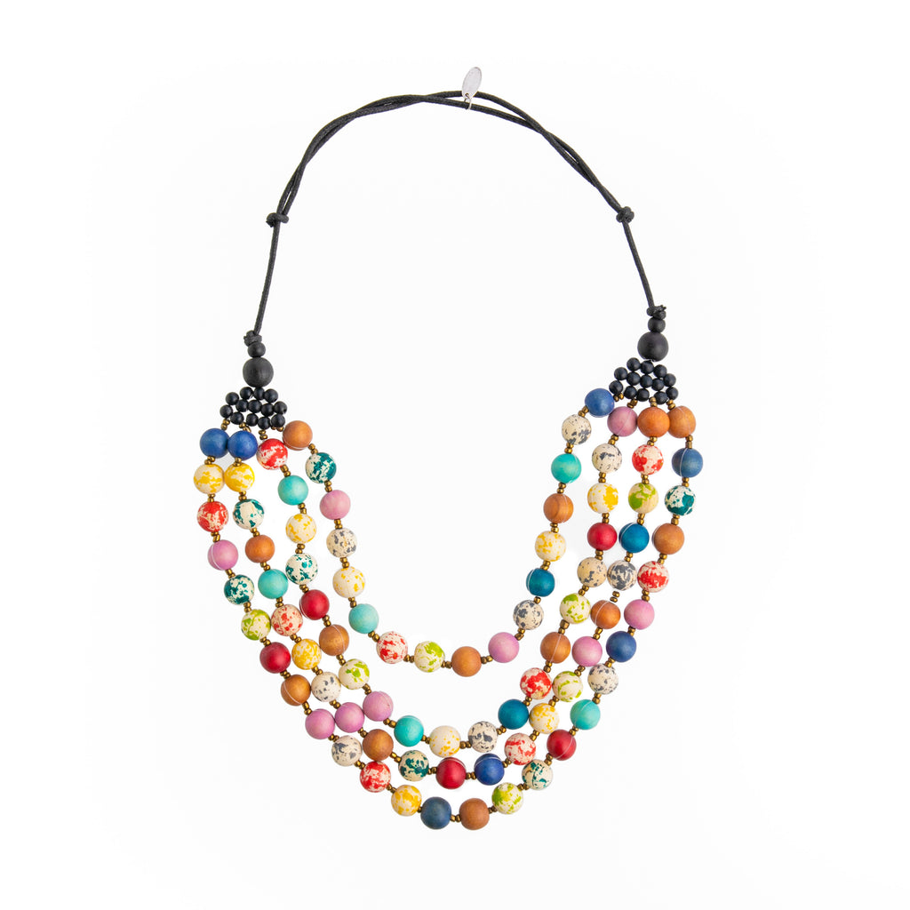 Four beautiful strands of hand-decorated wooden beads hang together to create this colorful statement necklace. Each strand lays within each other so that the necklace sits flat against your outfit. Materials: Hand-painted wood beads, waxed cotton cord. 20" in length with a 2" adjustable clasp.
