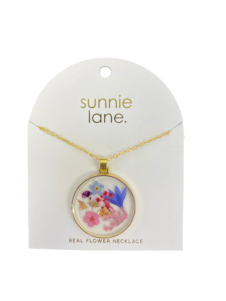 Carry the beauty of fresh flowers with you all day with this pretty pendant necklace featuring real pressed flowers encapsulated in lightweight resin. Chain length: 23.5" Pendant diameter: 1.2" Materials: Zinc alloy chain, resin, pressed flowers. Each necklace is unique and may differ slightly from the photo.