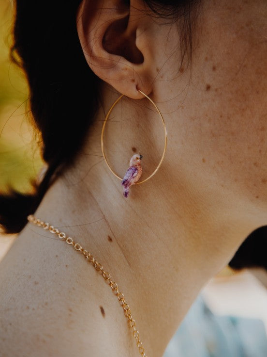 Add a tropical touch to your outfit with these adorable porcelain parrot hoop earrings. The porcelain parrots are painted by hand, making each pair of earrings unique. Porcelain and 24k gold plated brass earrings Designed in Toulouse, France Hoop diameter: 1.5"
