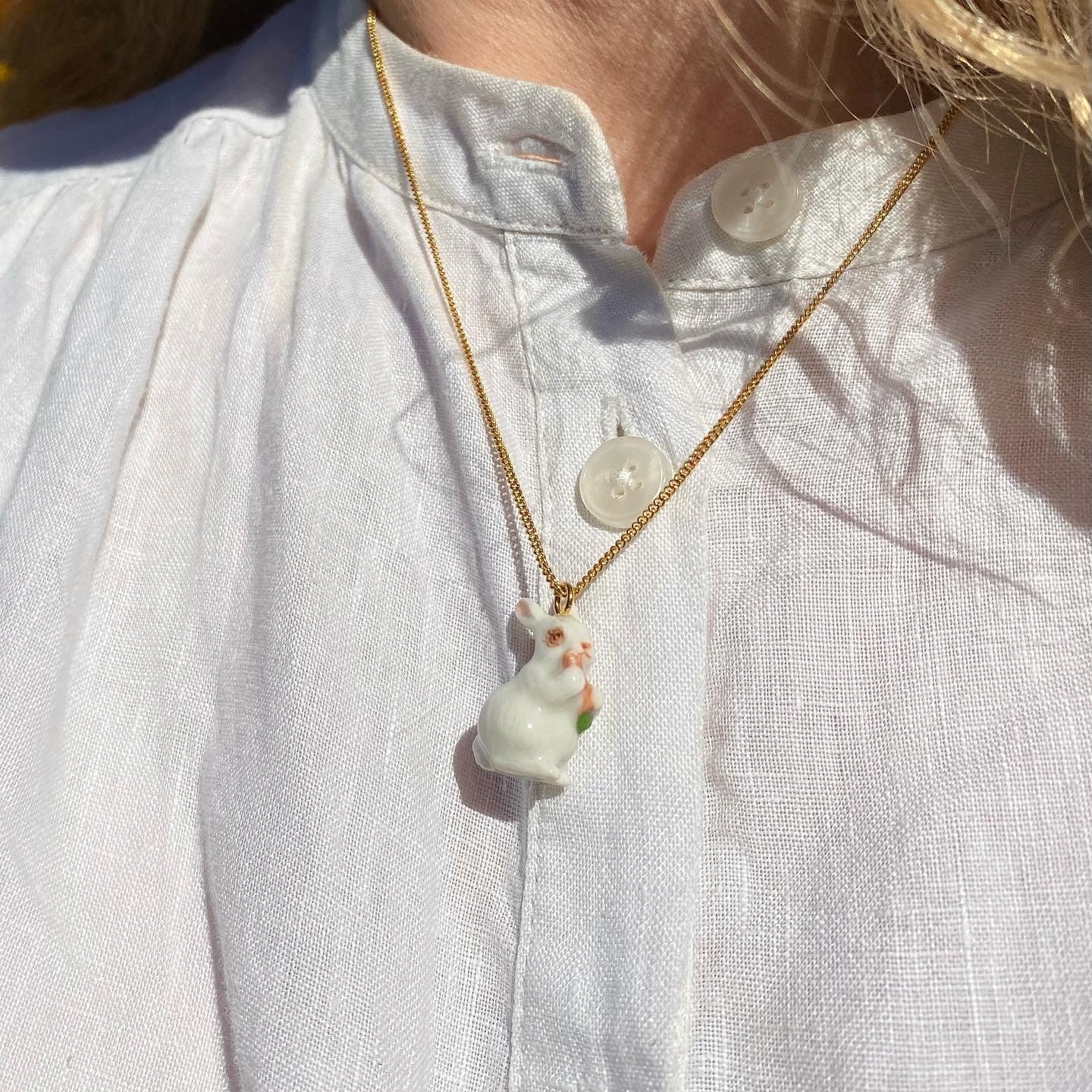 Keep a touch of springtime with you year-round with this adorable white rabbit necklace. Features a hand-painted porcelain bunny on a 24 carat gold plated chain. Porcelain and 24 carat gold plated over brass. Metal certified nickel free and allergy free. Chain length 19" Matching earrings available